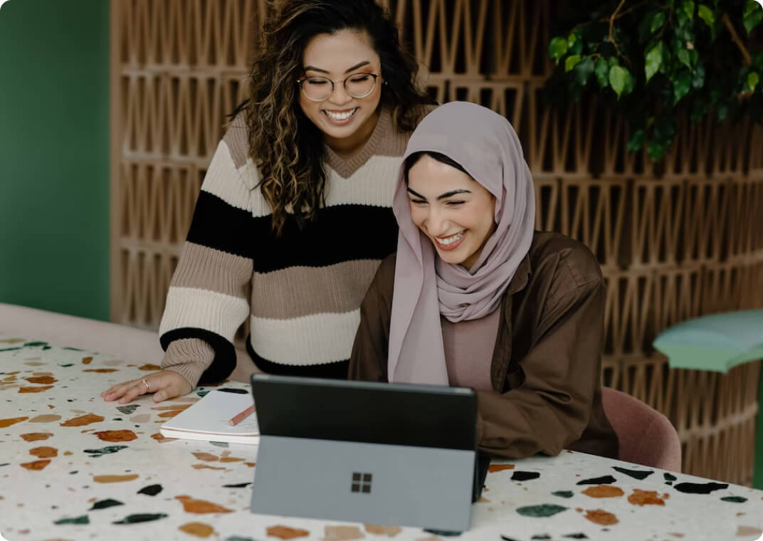 two women smiling in front of computer