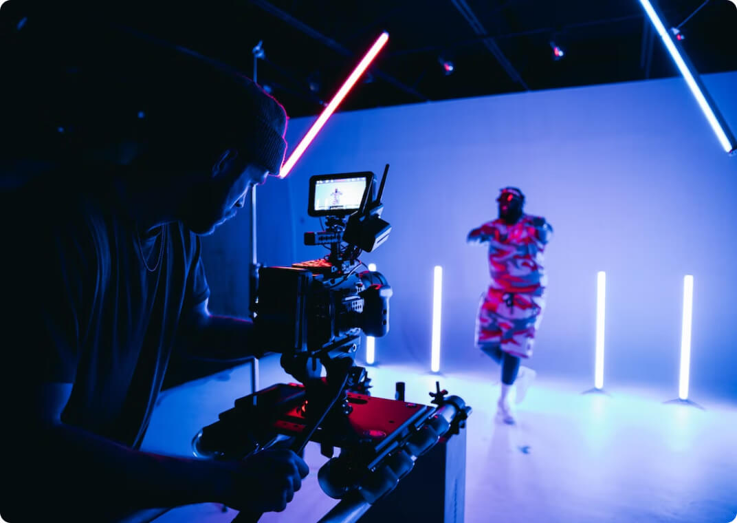 videographer filming man in camouflage against backdrop