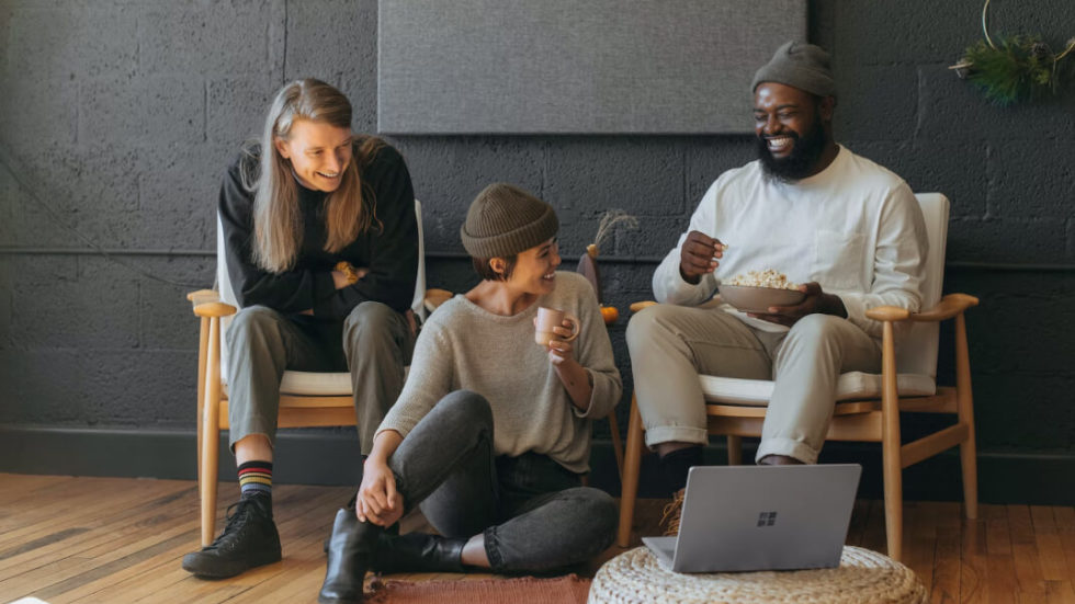 three happy people in casual setting with Windows computer and popcorn