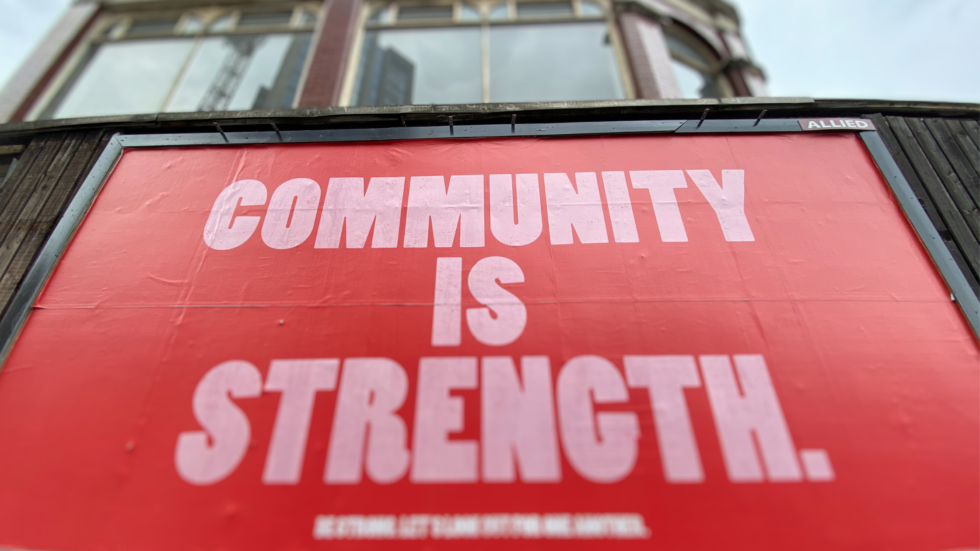 Building brand community: A close cropped image of a billboard. White text on a red background. Text reads: COMMUNITY IS STRENGTH.