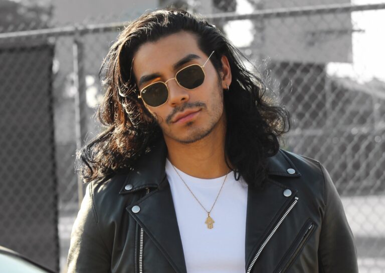 Male with long hair, white shirt and leather jacket wearing Ray Bans