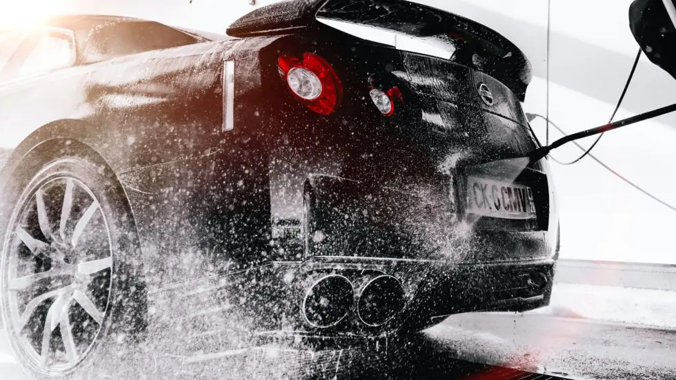 photo of a sports car being sprayed with a pressure washer