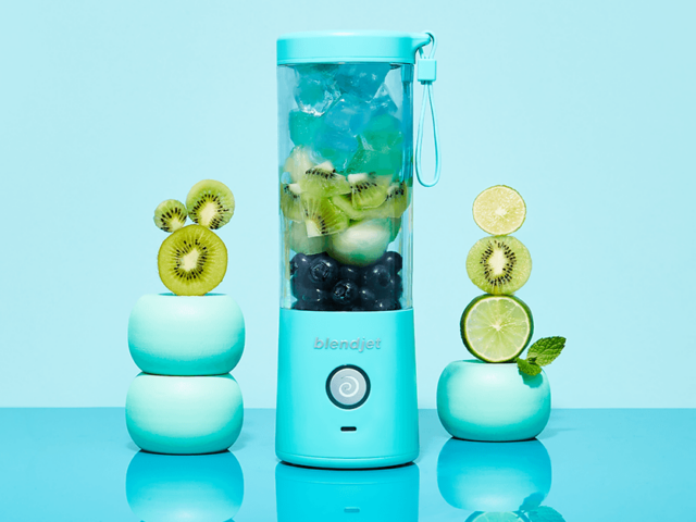 Image of a blue BlendJet Blender with kiwis, limes, blueberries, and ice.